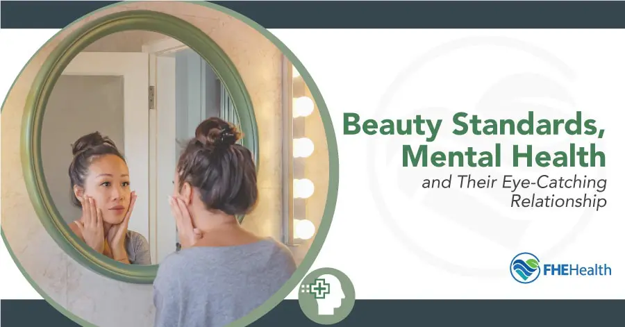 Picture of a woman looking in the mirror while struggling with unrealistic beauty standards
